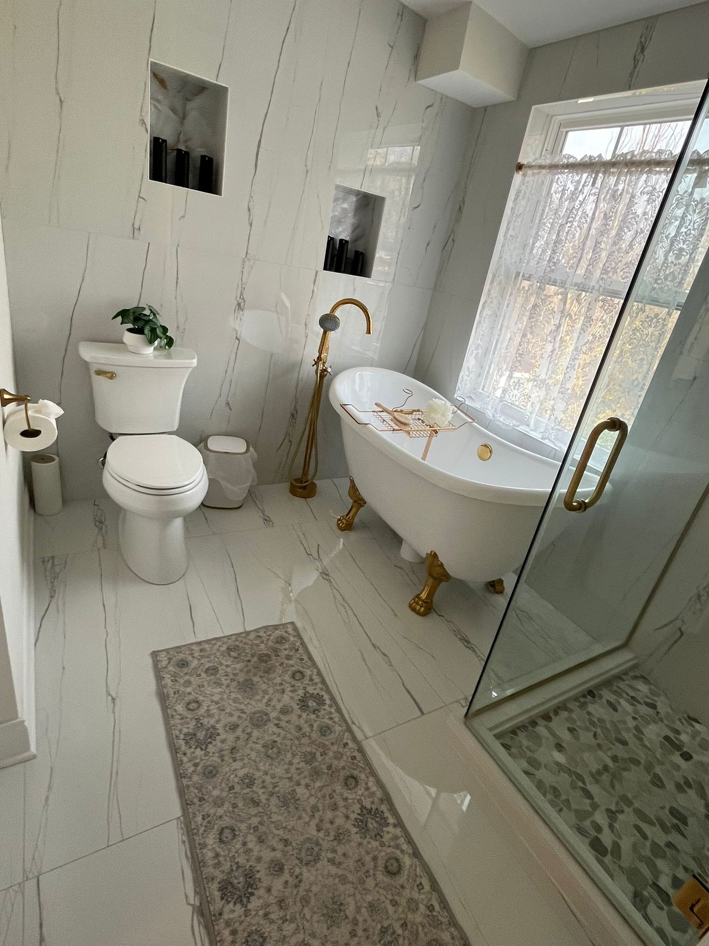 Elegant bathroom with a freestanding tub, glass shower, and white marble walls.